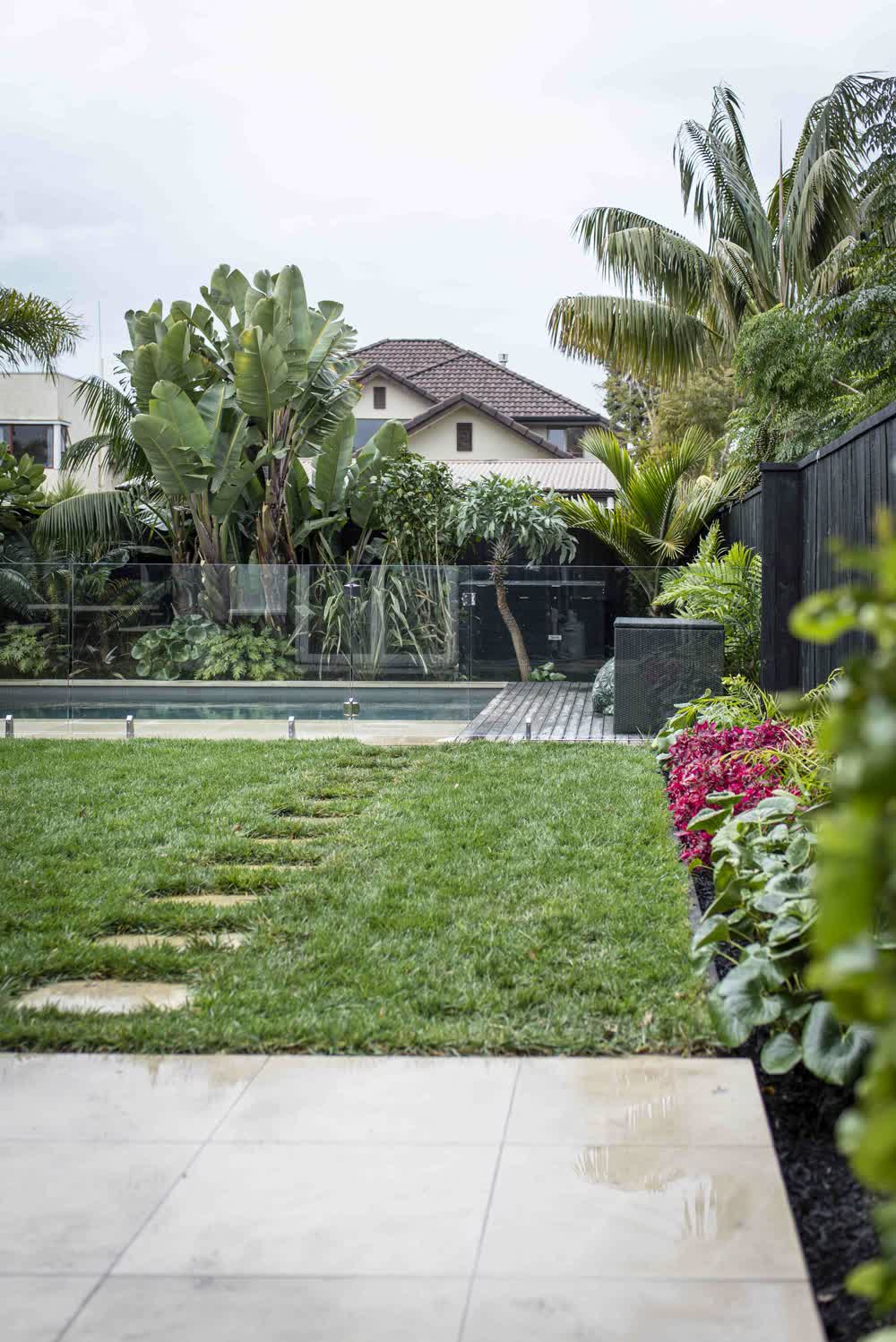 Lawn with paver path between patio and pool